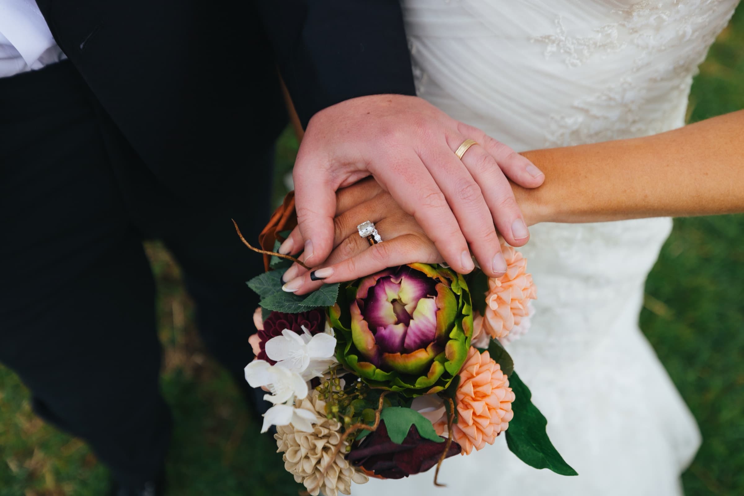 Jami and JJ's hands resting on her bouquet, wedding rings visible